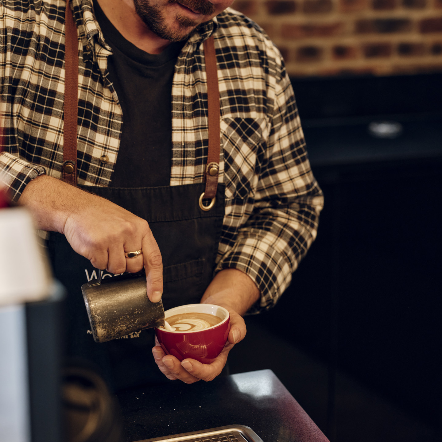 Barista pouring flat white coffee in Jersey Work Cafe
